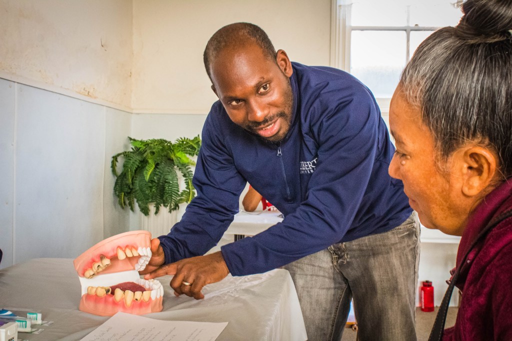 man using teeth model to educate woman